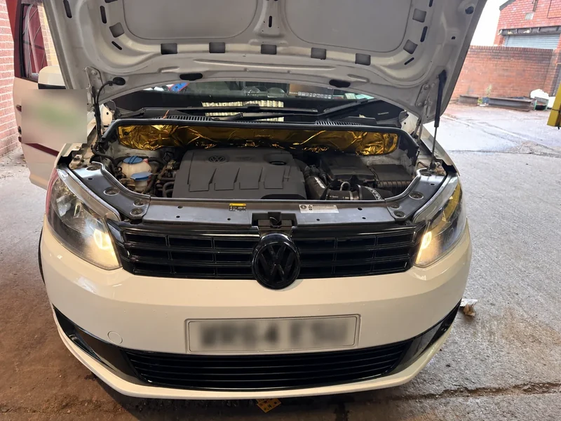 VW Caddy engine bay in the workshop with registration and visible contact details obscured for privacy